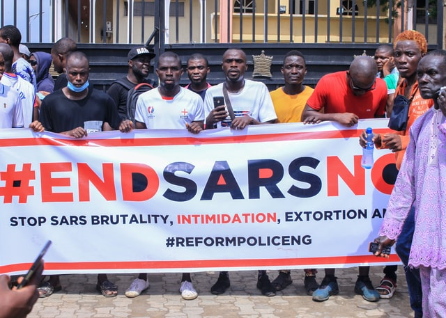 Photo by Tobi Oshinnaike on Unsplash. Nigerian Citizens holding up a #ENDSARSNOW Poster