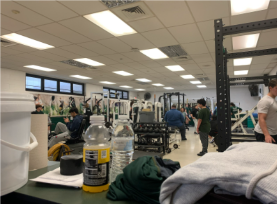 Students, on a Thursday, put in work in the Kinnelon High School fitness center. While some pictured are on stationary bikes, others are using the squat racks. In the back, some are doing pull ups right by the big mirror. 