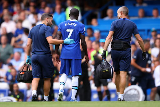 Image from GettyImages. N’Golo Kante being escorted off the field after sustaining an injury in a premier league match for Chelsea FC.