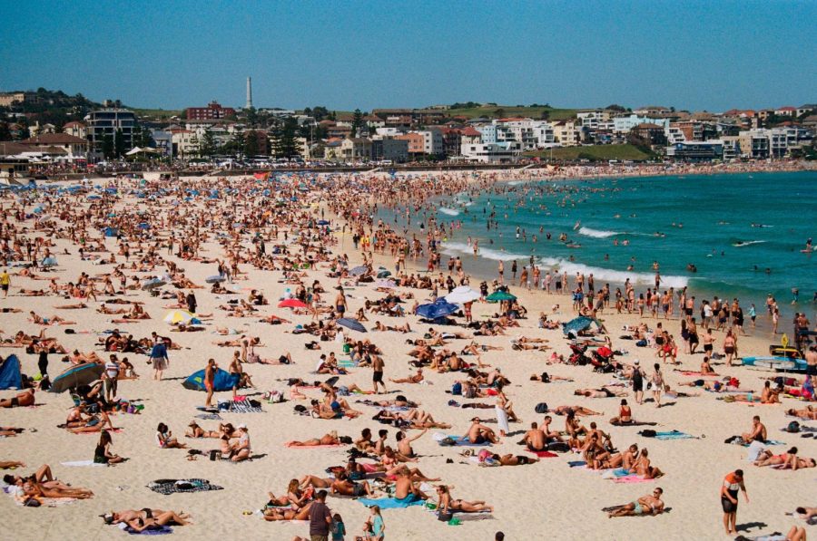 A large crowd of people relax on the beach during spring break.