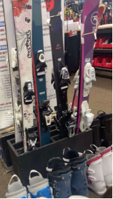 Students gather pairs of skis and boots are placed in a line at the store for the upcoming ski season.