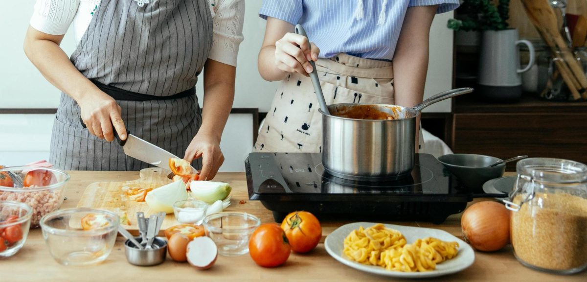 women cooking at stove in kitchen