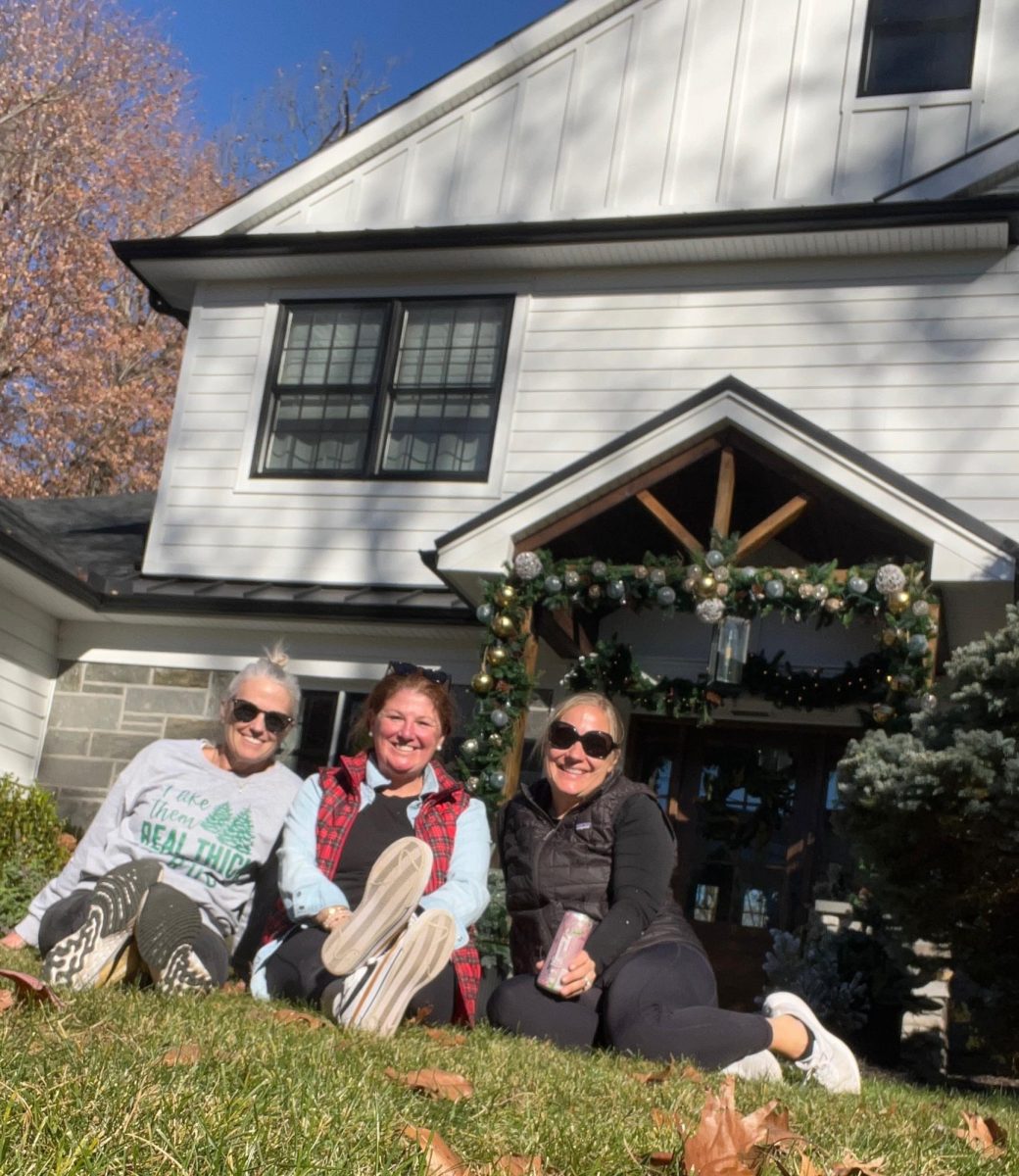 The three business owners are outside a house they decorated. 