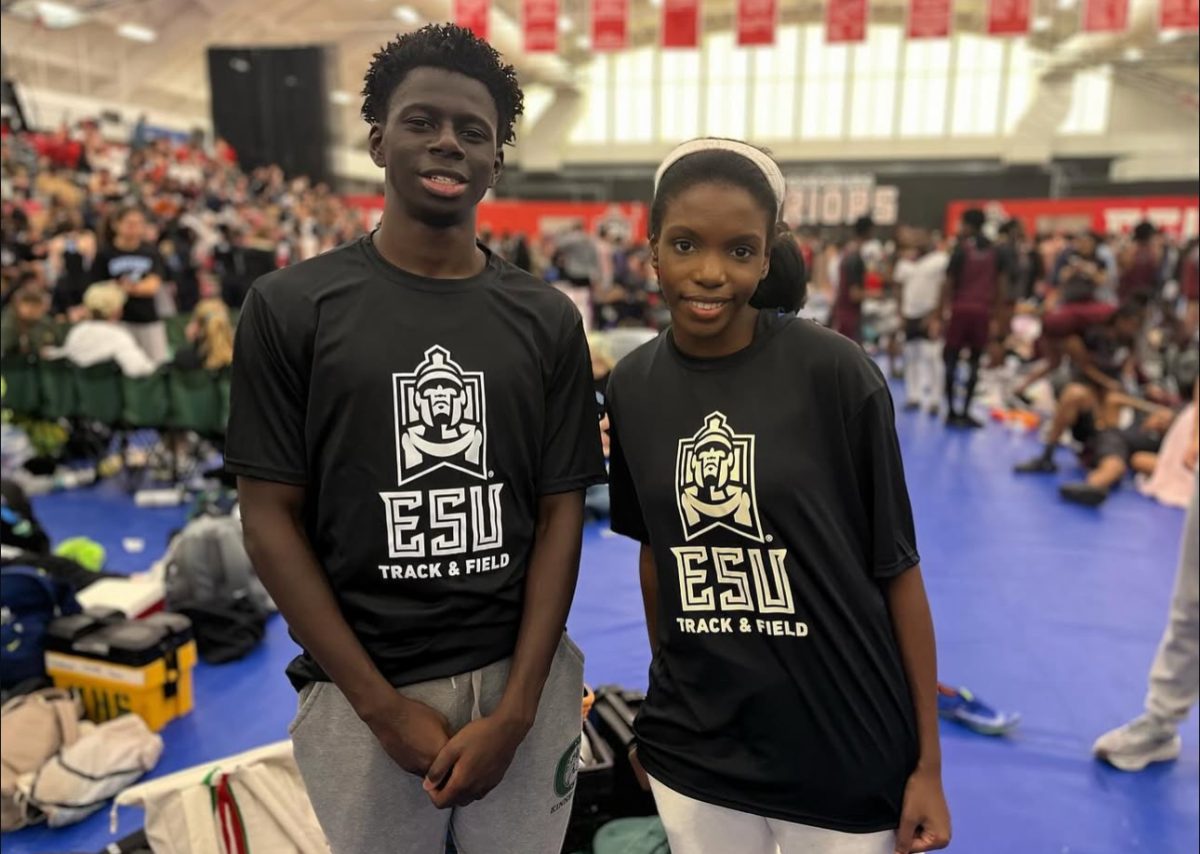 Hinton (right) and teammate Joseph Mendy pose at a track meet.