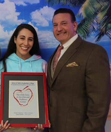 Baskinger (left) holds a certificate for the grant with superintendent David Mango.